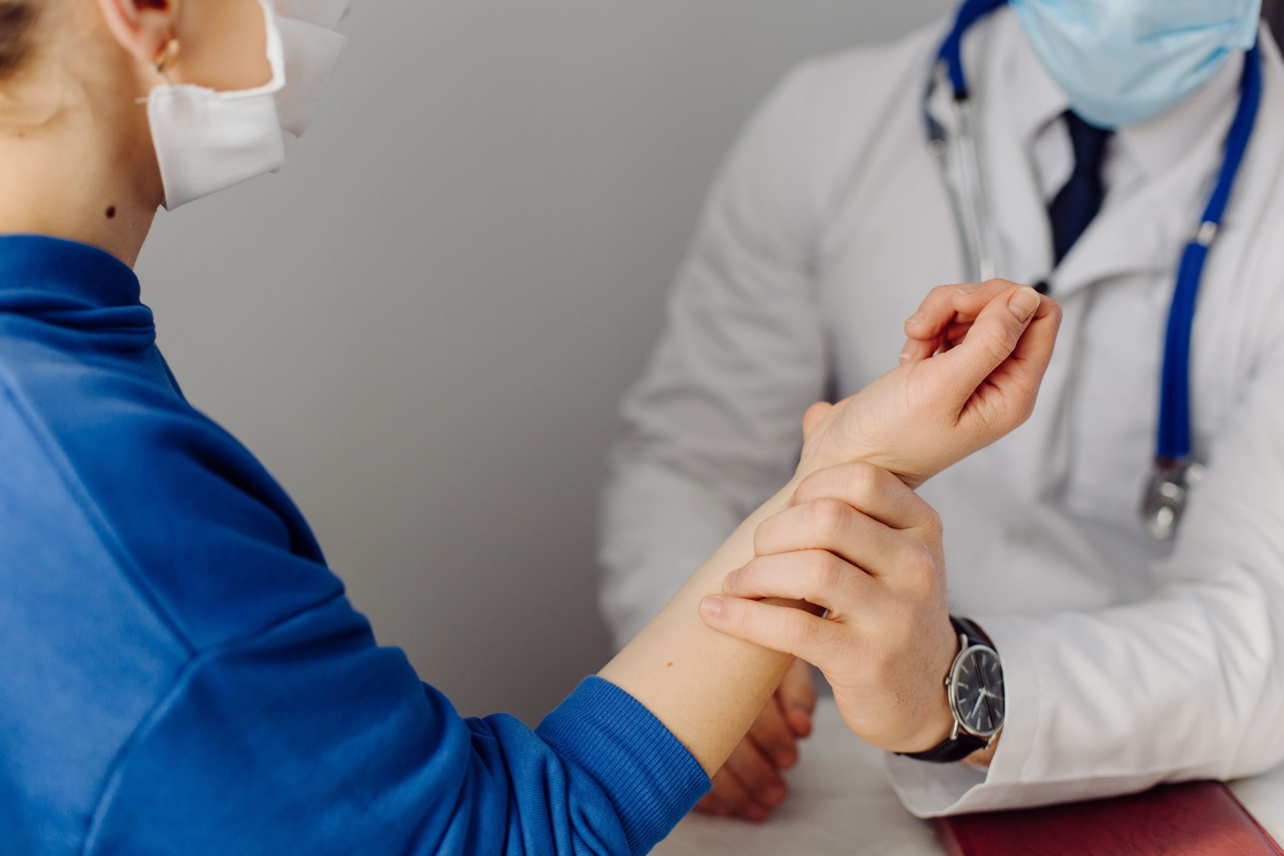 A medical professional examining a patient's wrist during a consultation.